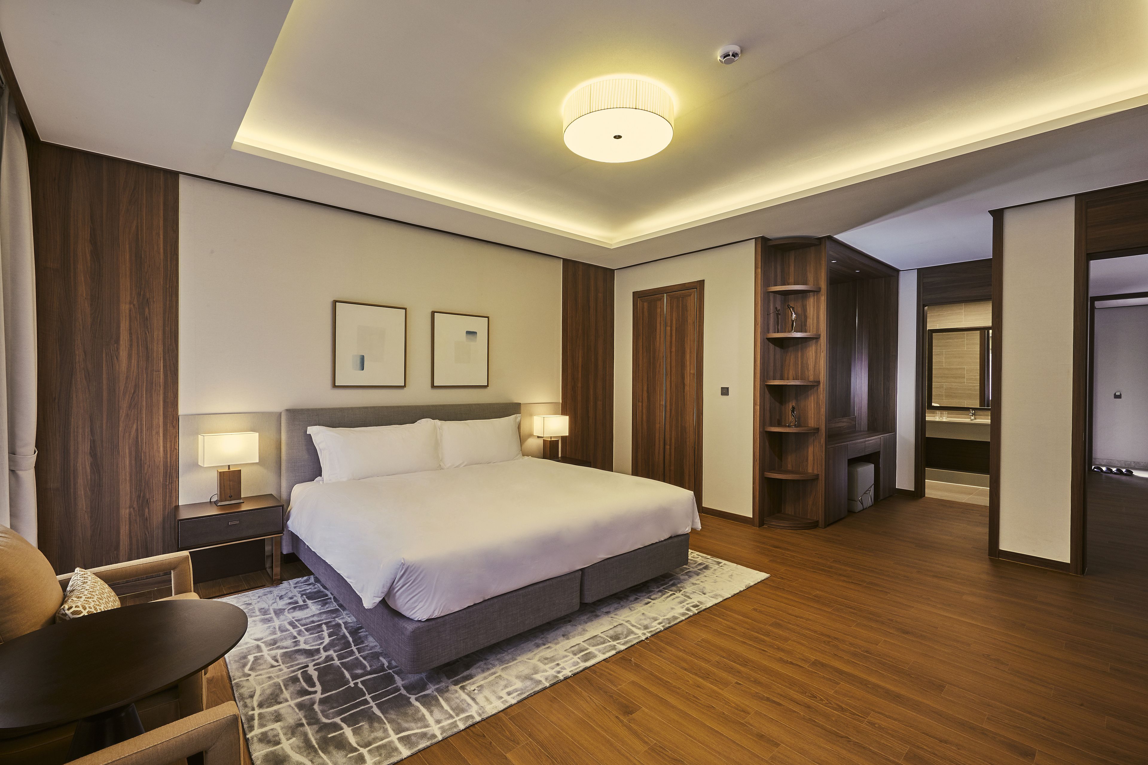 Ein modernes Hotelzimmer mit einem großen Bett, Nachttischen, einem Schreibtisch und einem Kleiderschrank.