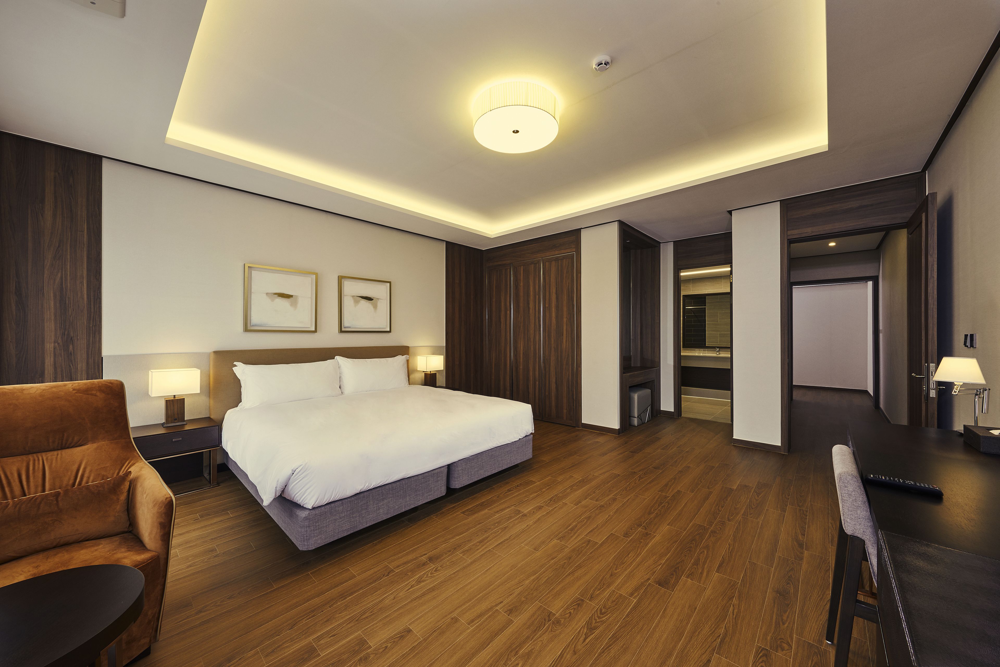 A modern hotel room with a large bed, a sofa, a desk, and a TV.