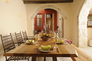 A dining table set with plates, glasses, and a bowl of fruit. - Veranda Rossa Suites (Rethymno)