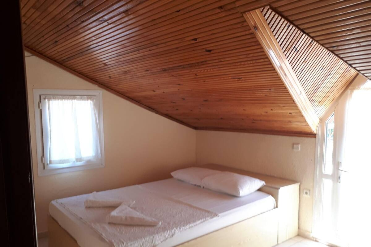 A small, single-bed room with a sloped ceiling and a window.