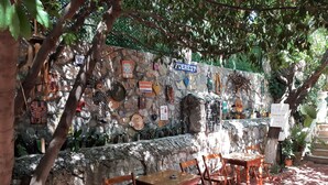 An outdoor seating area with stone walls, wooden furniture, and various signs and decorations. - Everest Apart Hotel (Fethiye)