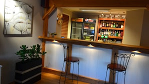 A bar area with two stools, a refrigerator, shelves with bottles, and a clock on the wall. - Vikedal Vertshus (Vindafjord)