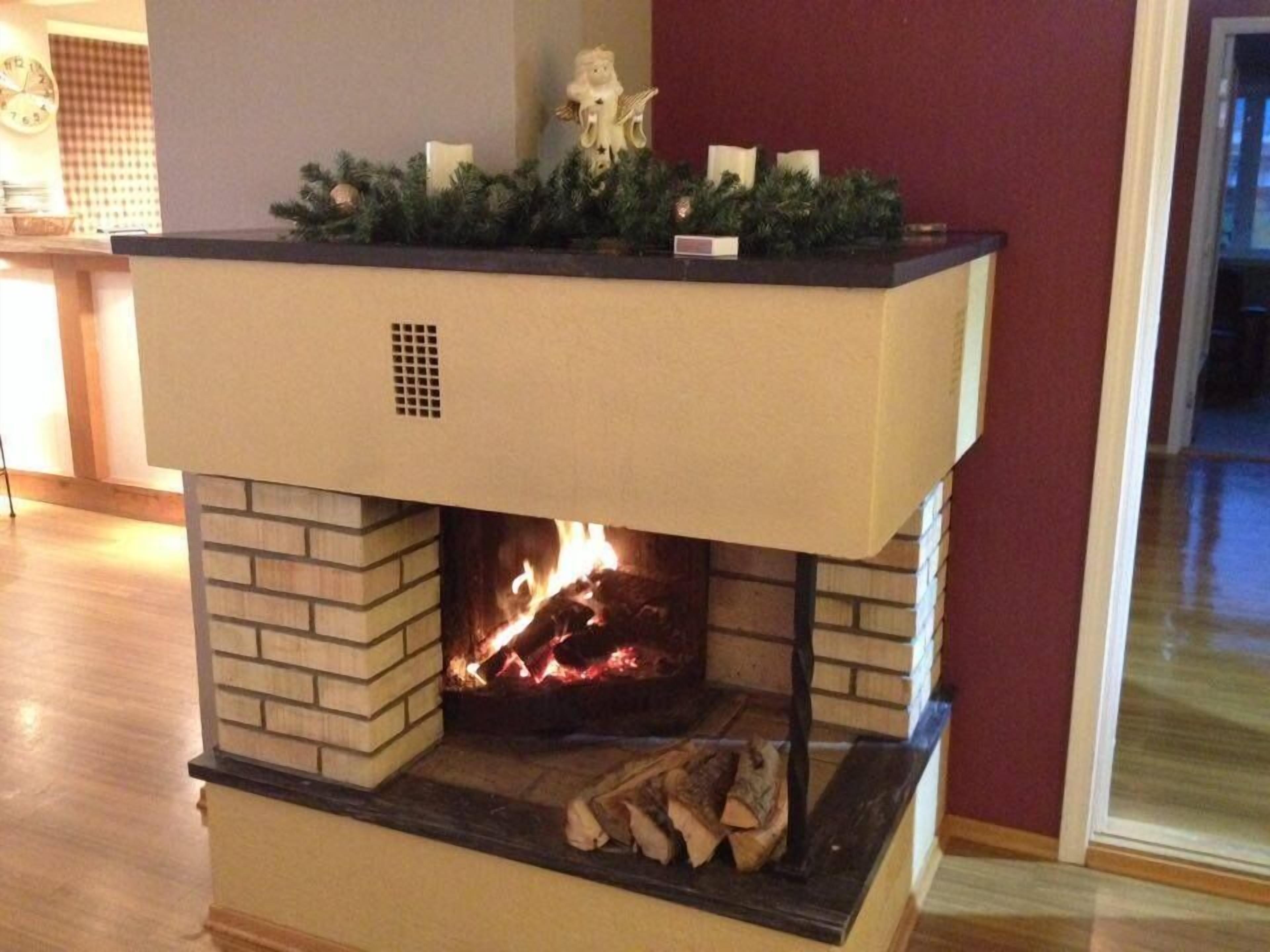 Una chimenea con repisa decorada con follaje y velas, un revestimiento de ladrillo y fuego visible.