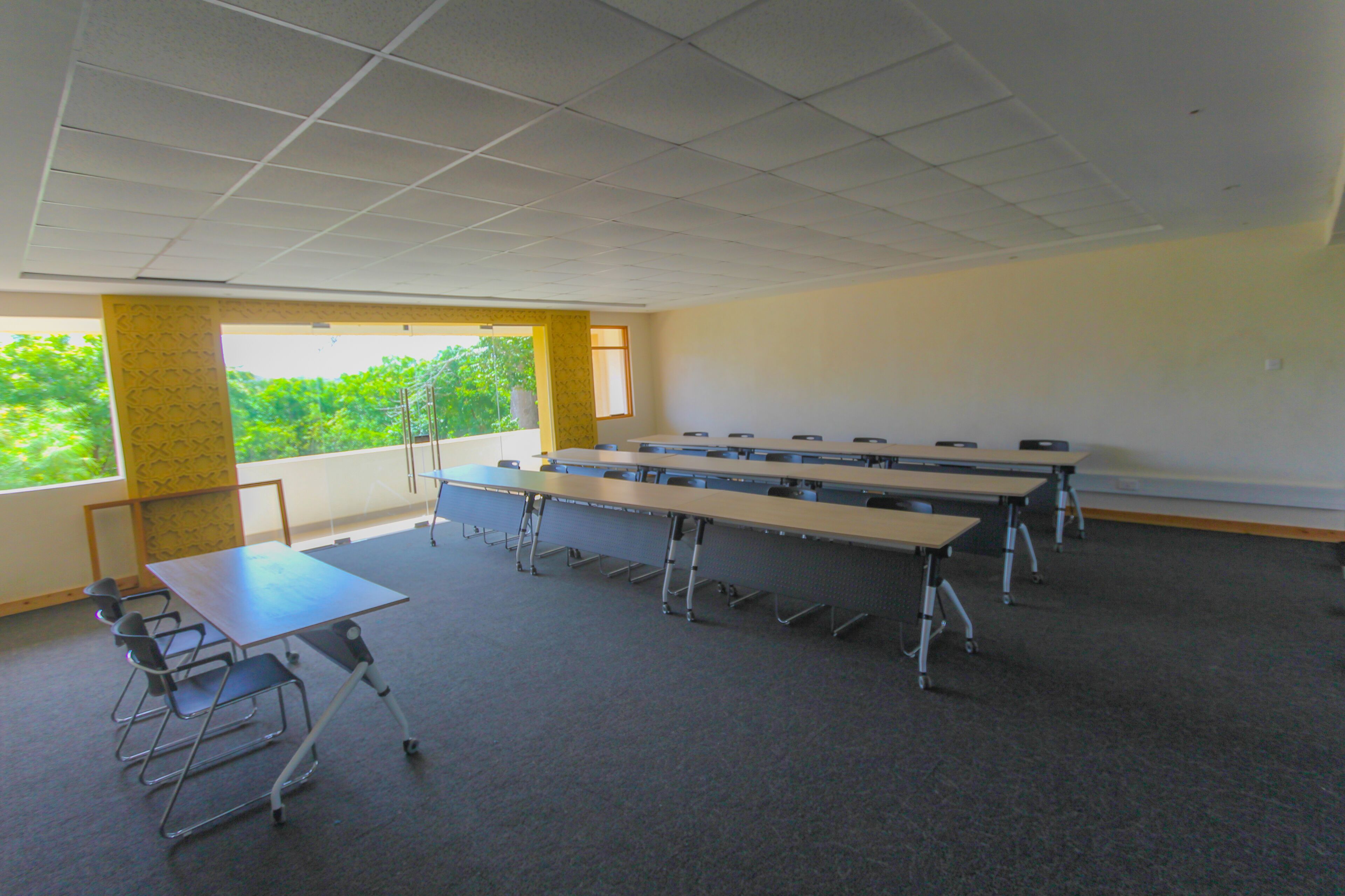 A conference room with a long table, chairs, and a projector screen.