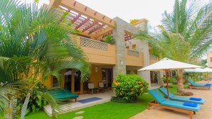 Un edificio de dos pisos con un patio que tiene sillones y sombrillas.