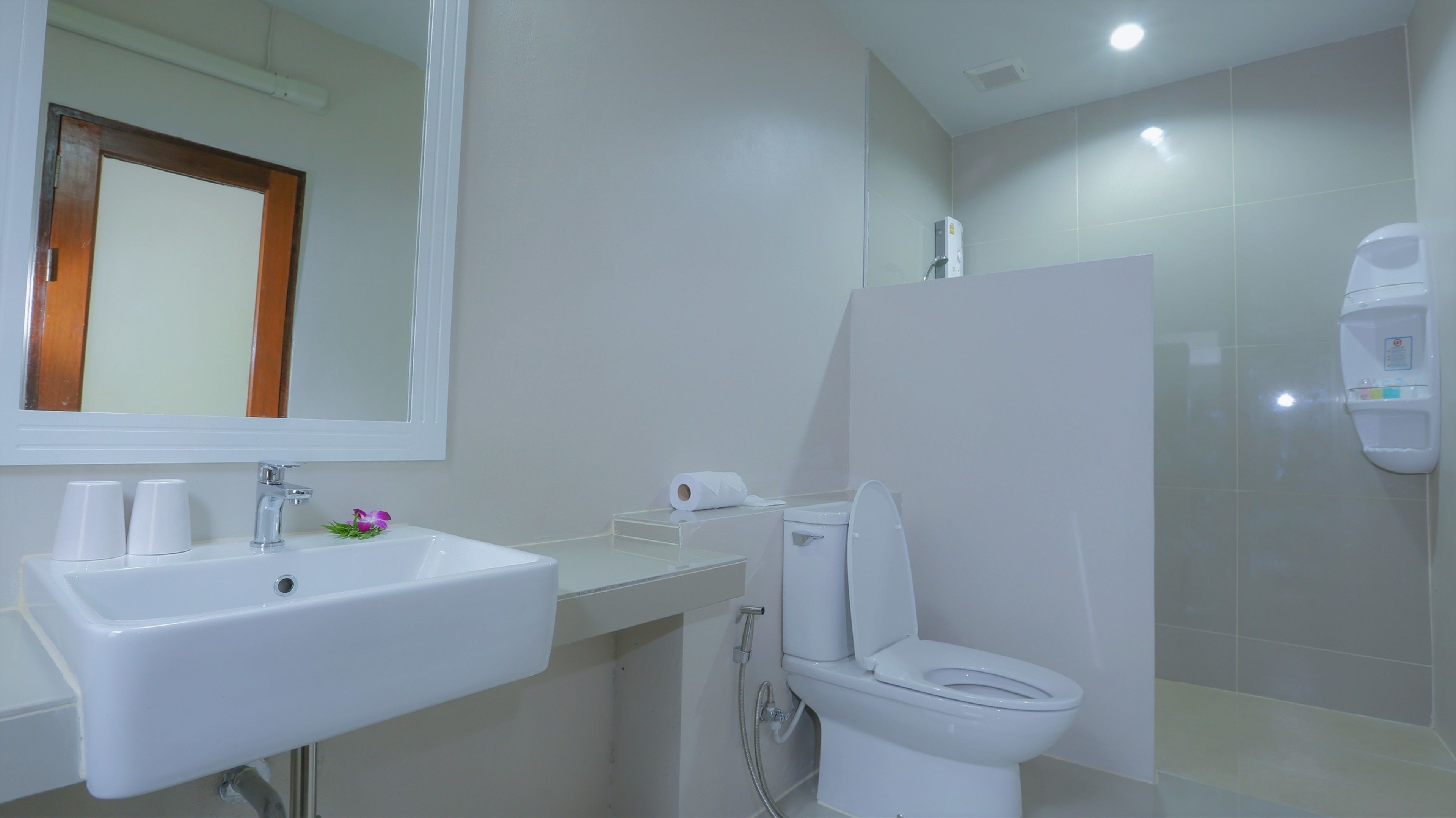 A bathroom with a white sink, mirror, toilet, and shower.