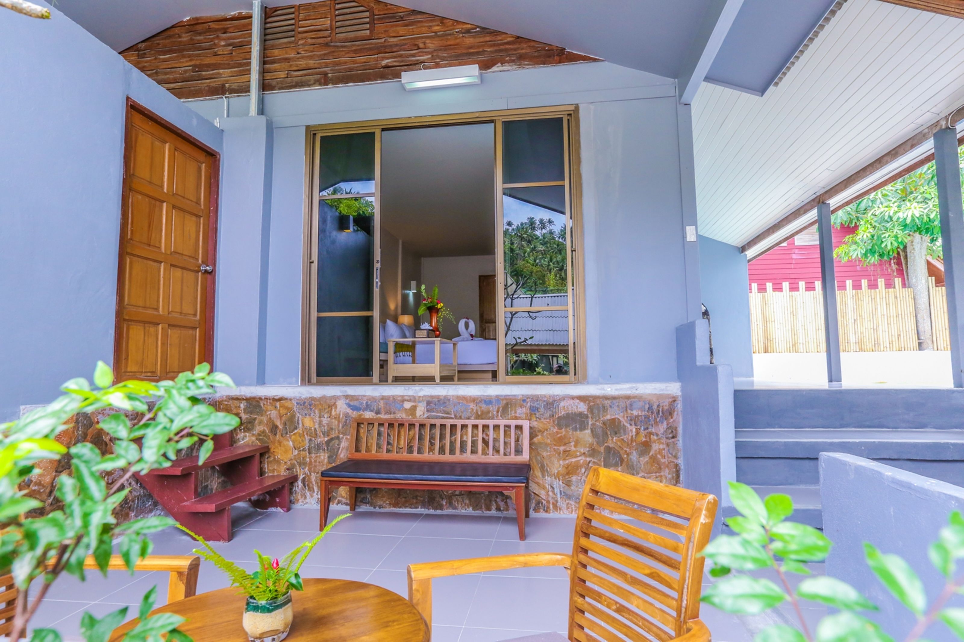 A patio area with a wooden bench, a table, and potted plants.