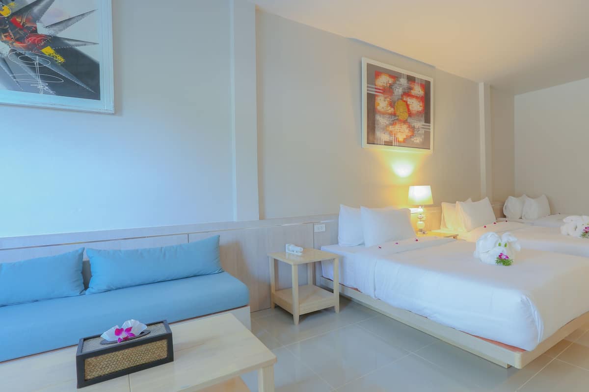 A hotel room with two beds, a sofa, a small table, and a painting on the wall.