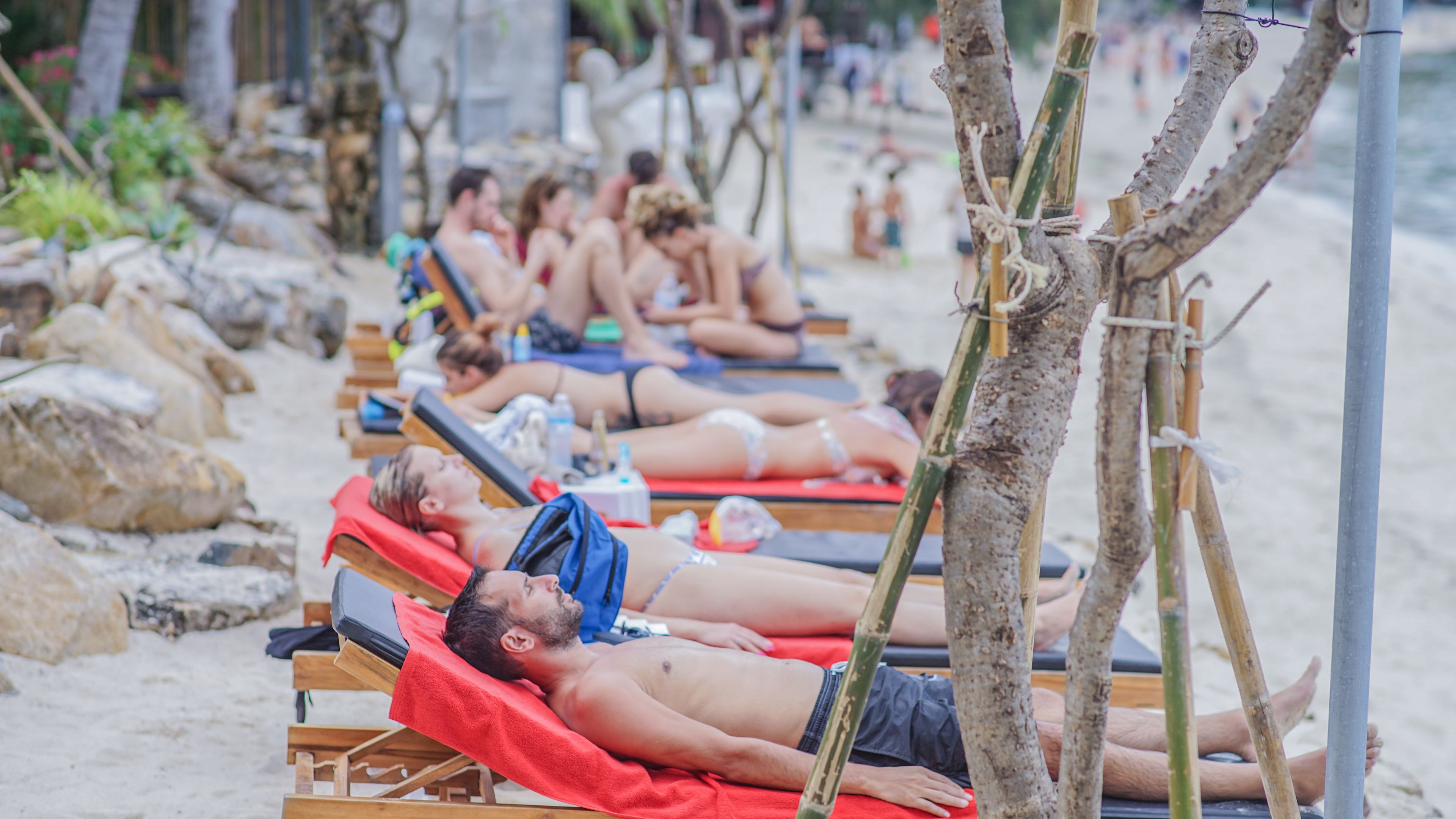 Une plage avec des transats et des gens qui prennent des bains de soleil.