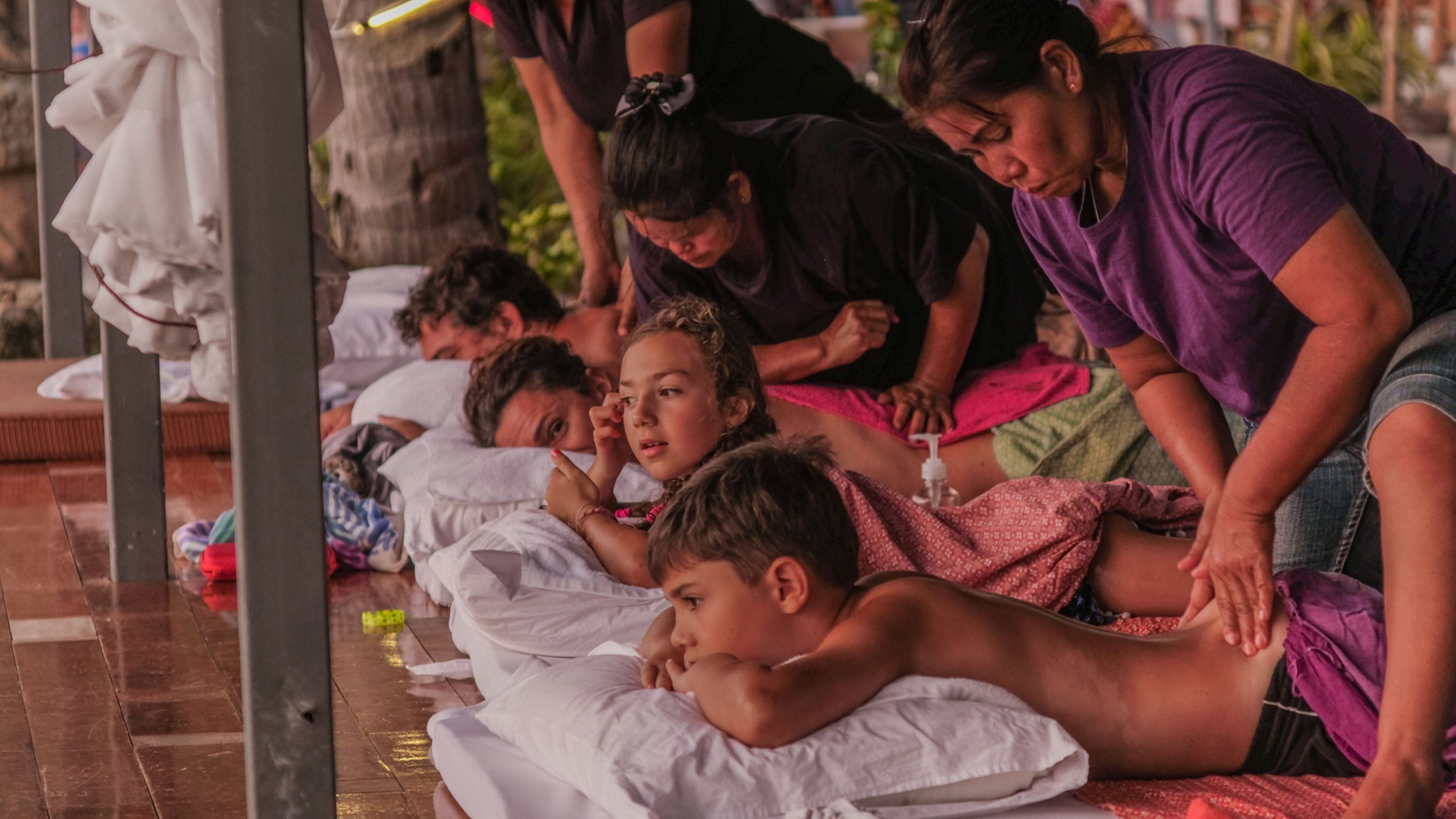 A group of people lying on the floor, possibly in a waiting area or a temporary shelter.
