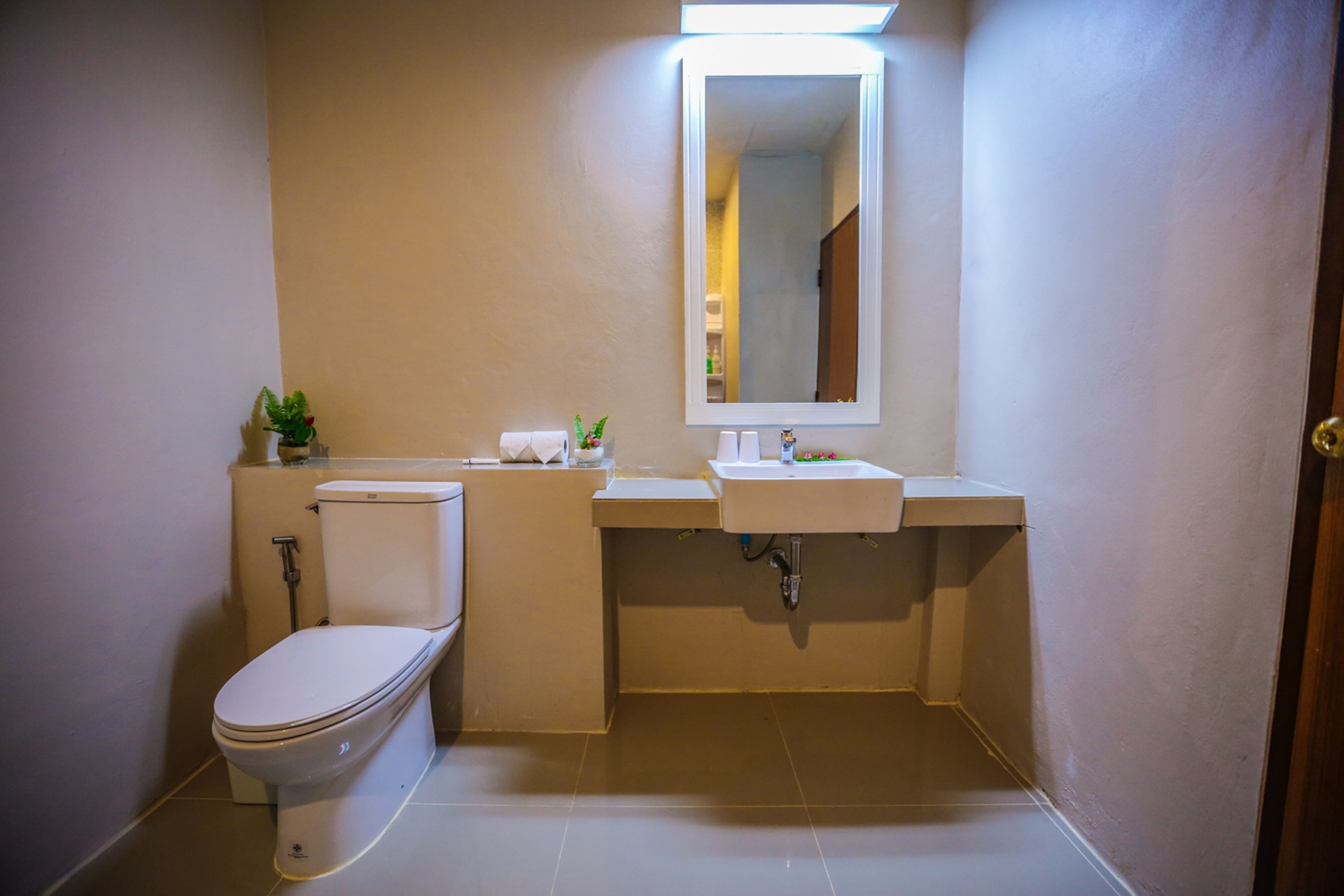 A bathroom with a toilet, sink, and mirror.