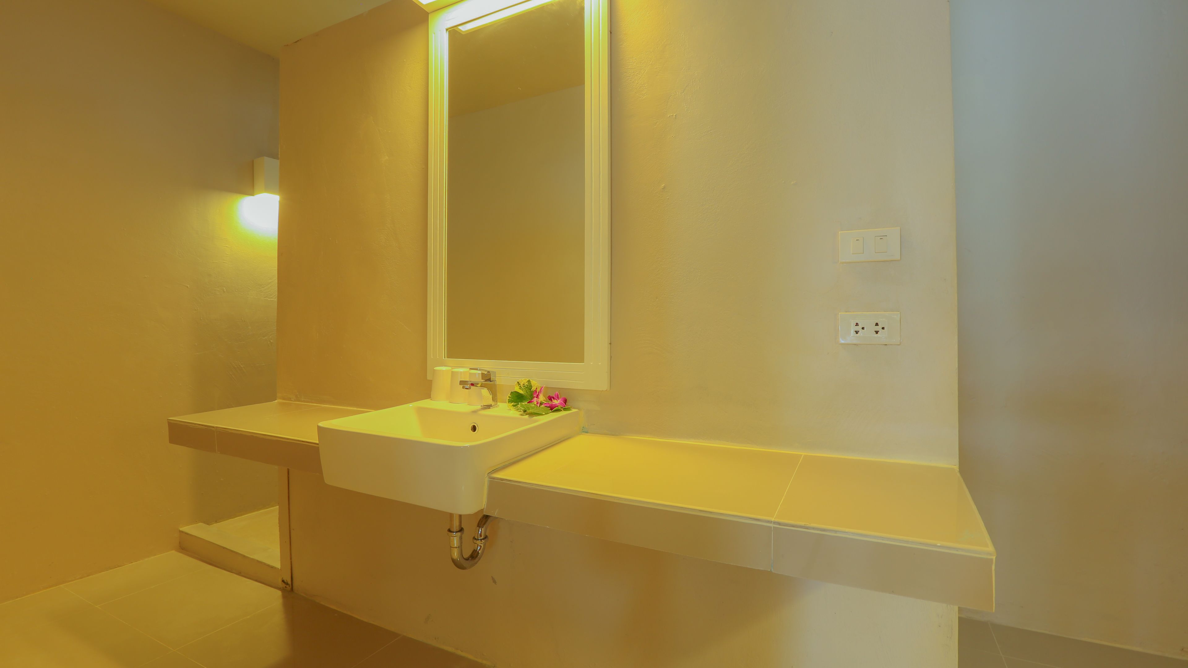 A bathroom with a white sink, a mirror, and a light fixture above the mirror.