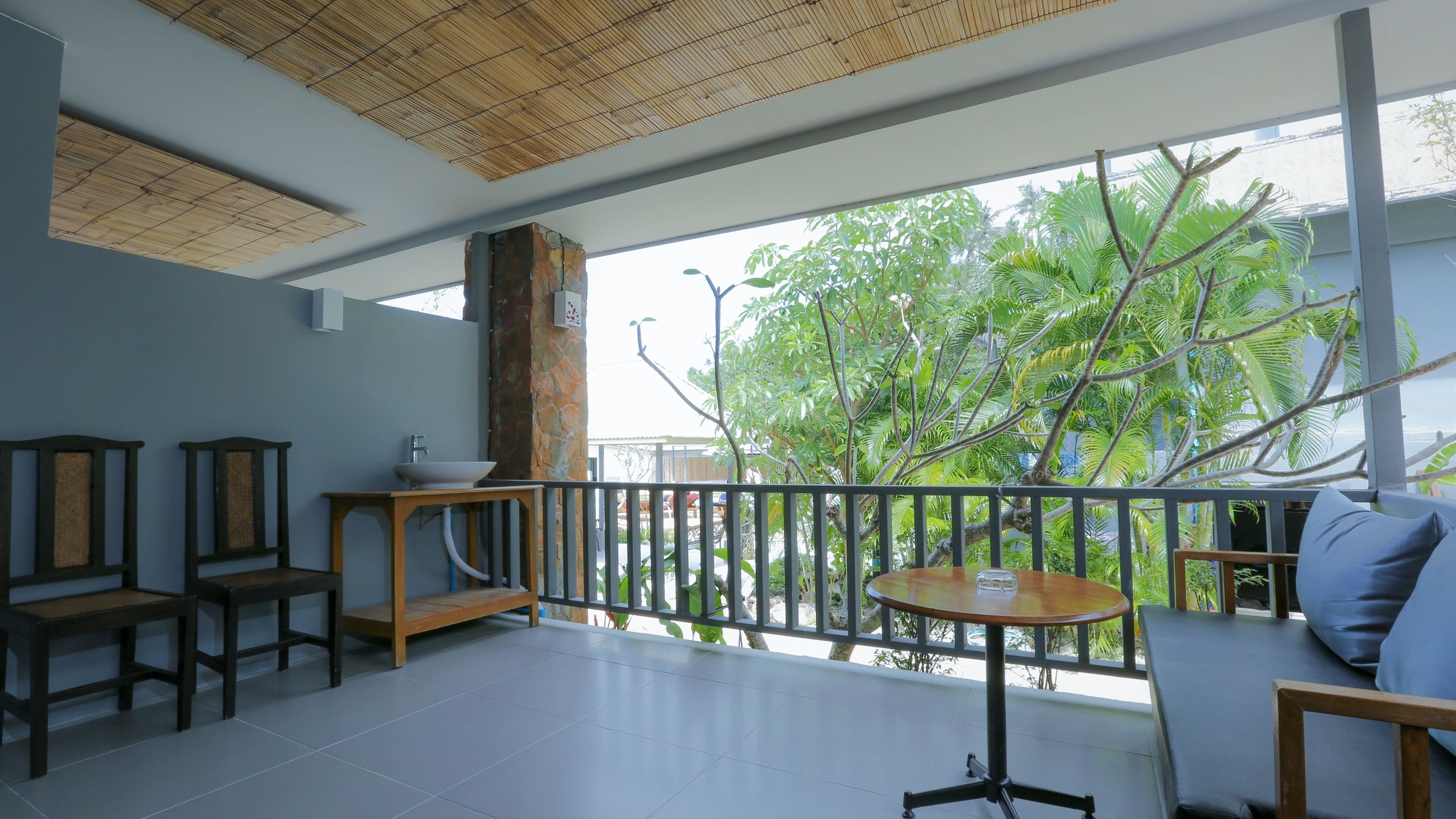 A balcony with a view of trees, a wooden table, and two chairs.