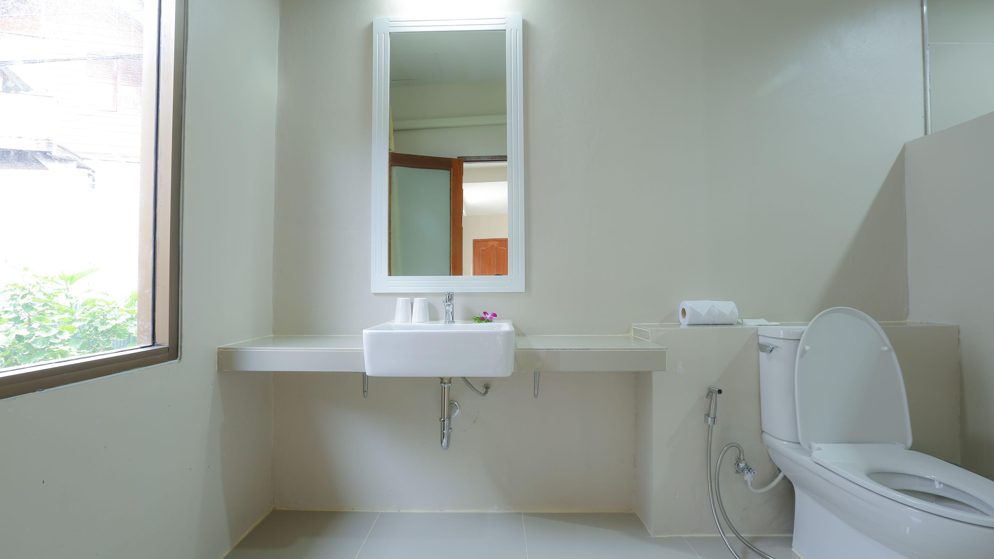 A bathroom with a white sink, mirror, and toilet.