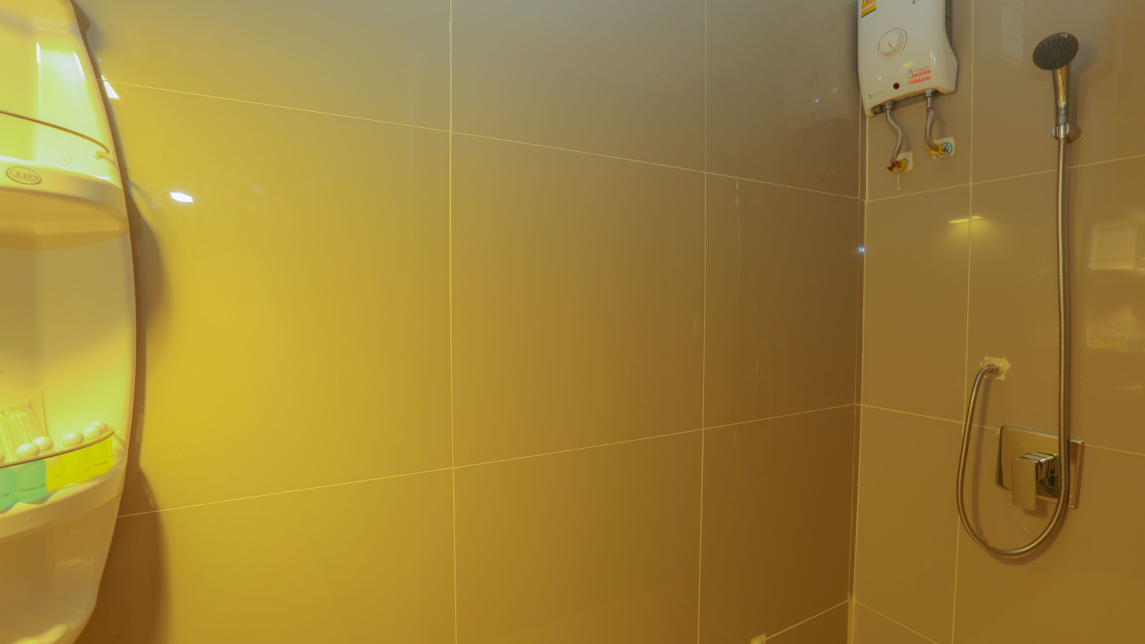 A bathroom with a shower, a toilet, and a glass of water on the sink.