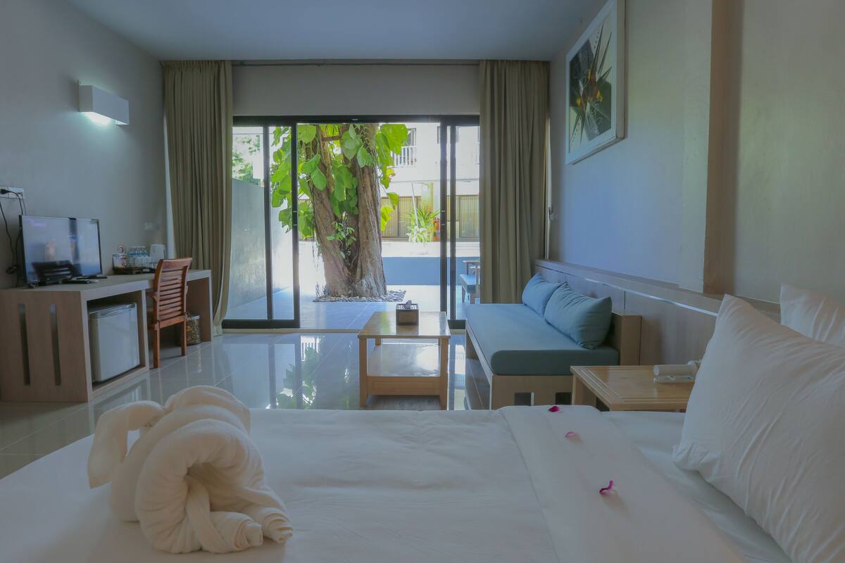 A hotel room with a bed, a sofa, a TV, and a desk.