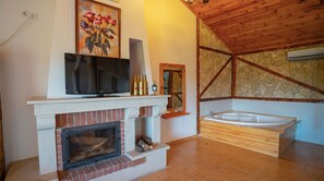A room with a fireplace, a television, a mirror, and a stone wall. - Agva Masal Evi (Sile)
