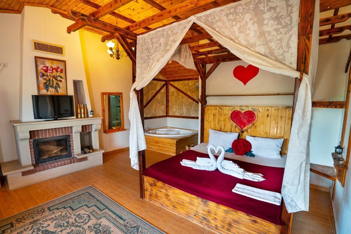 Um quarto acolhedor com uma cama de dossel, lareira e televisão.
