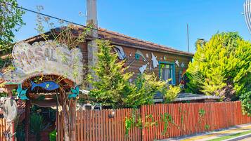 A building with a distinctive sign, a wooden fence, and a variety of plants.
