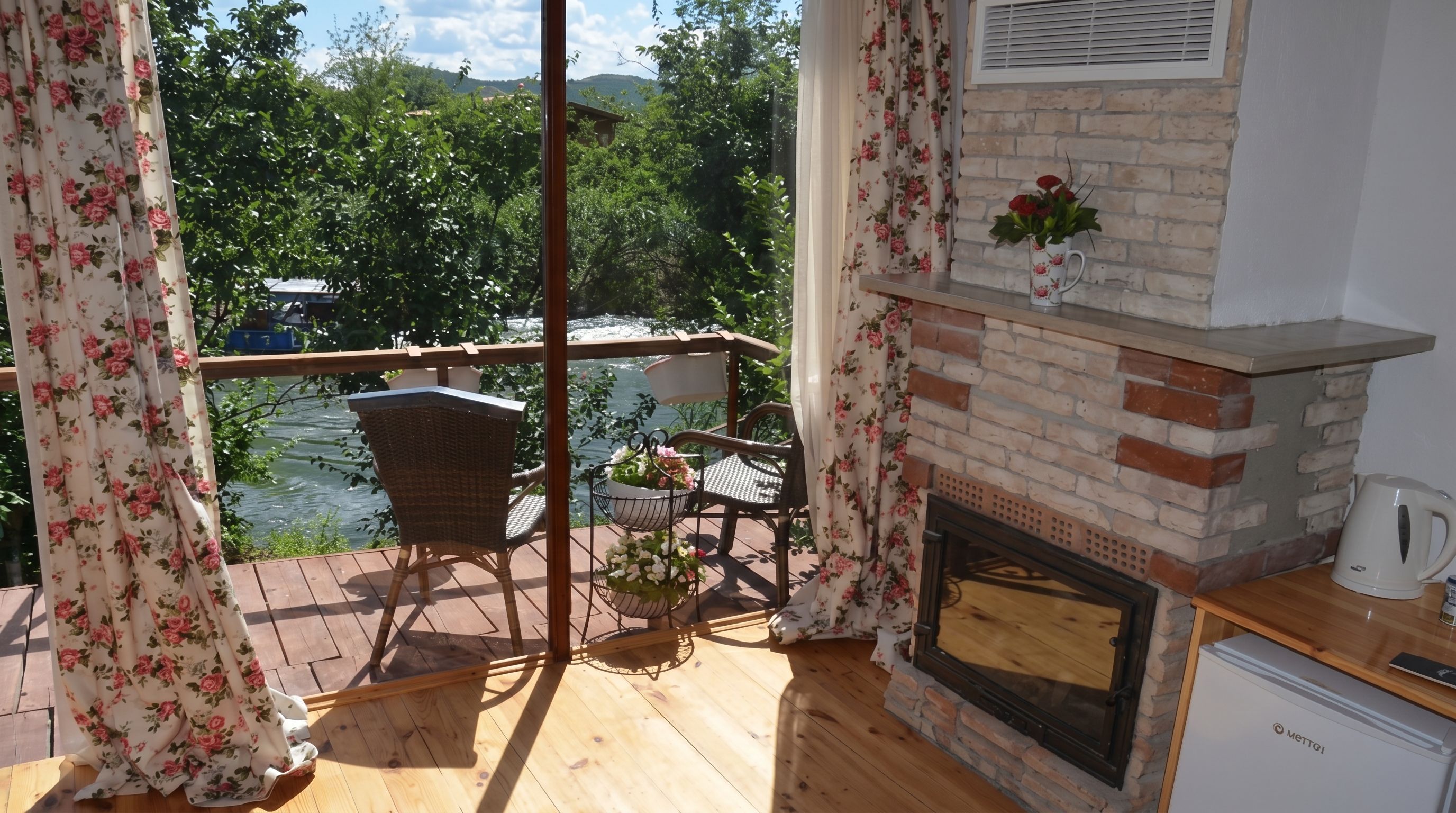 Un balcón con mobiliario de mimbre, una chimenea de ladrillo y vistas a un río.