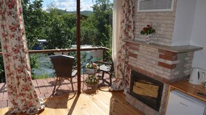 A balcony with wicker furniture, a brick fireplace, and a view of a river. - Agva Masal Evi (Sile)