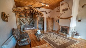 L’intérieur d’un chalet rustique, avec une cheminée en pierre, des meubles en bois et une grande baignoire.