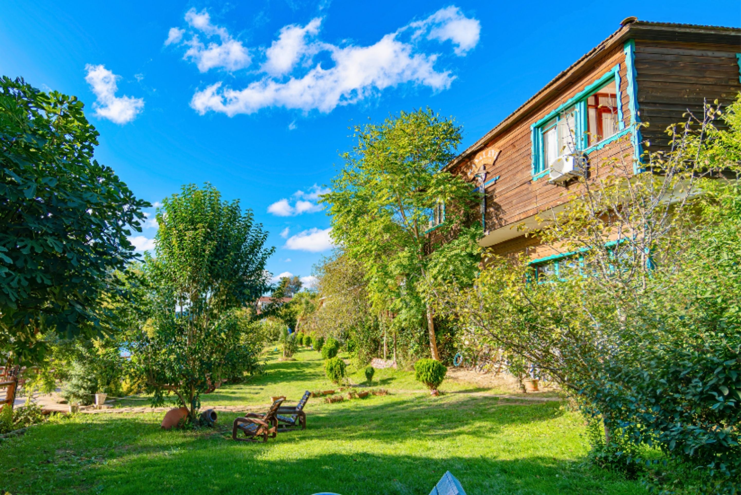A wooden house with a garden, a lawn, and a clear blue sky.
