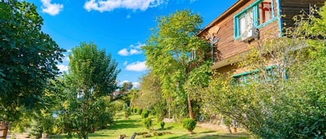 A wooden house with a garden, a lawn, and a clear blue sky.