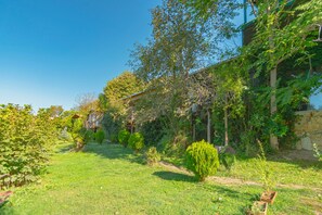 A garden with a variety of plants and a building with a stone wall. - Agva Masal Evi (Sile)
