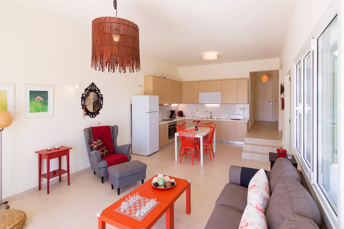 Een modern appartement met een zithoek, eetgedeelte, keuken en een trap naar een verdieping.