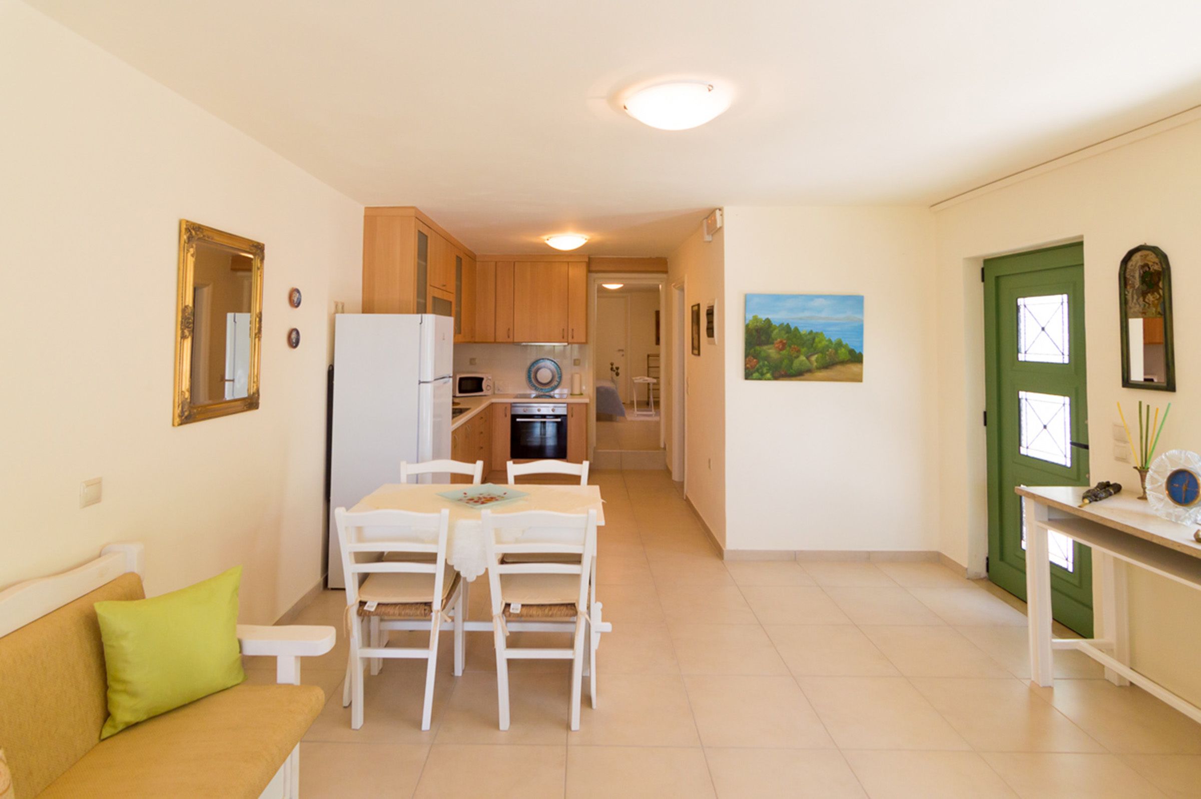 Un espacio habitable compacto con kitchenette, comedor y puerta verde.