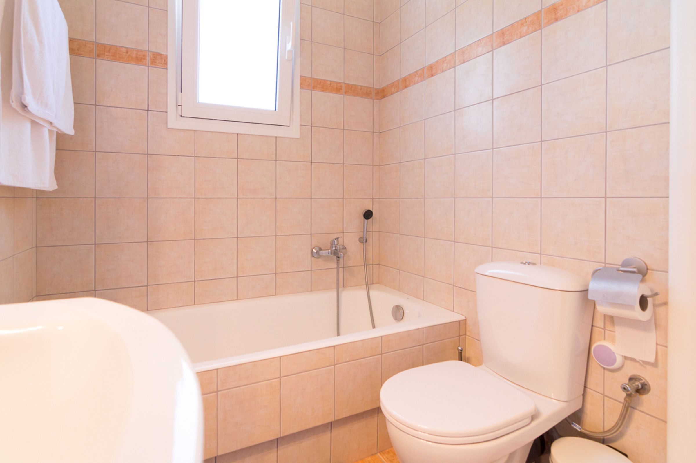 Un baño con bañera, inodoro y ventana.