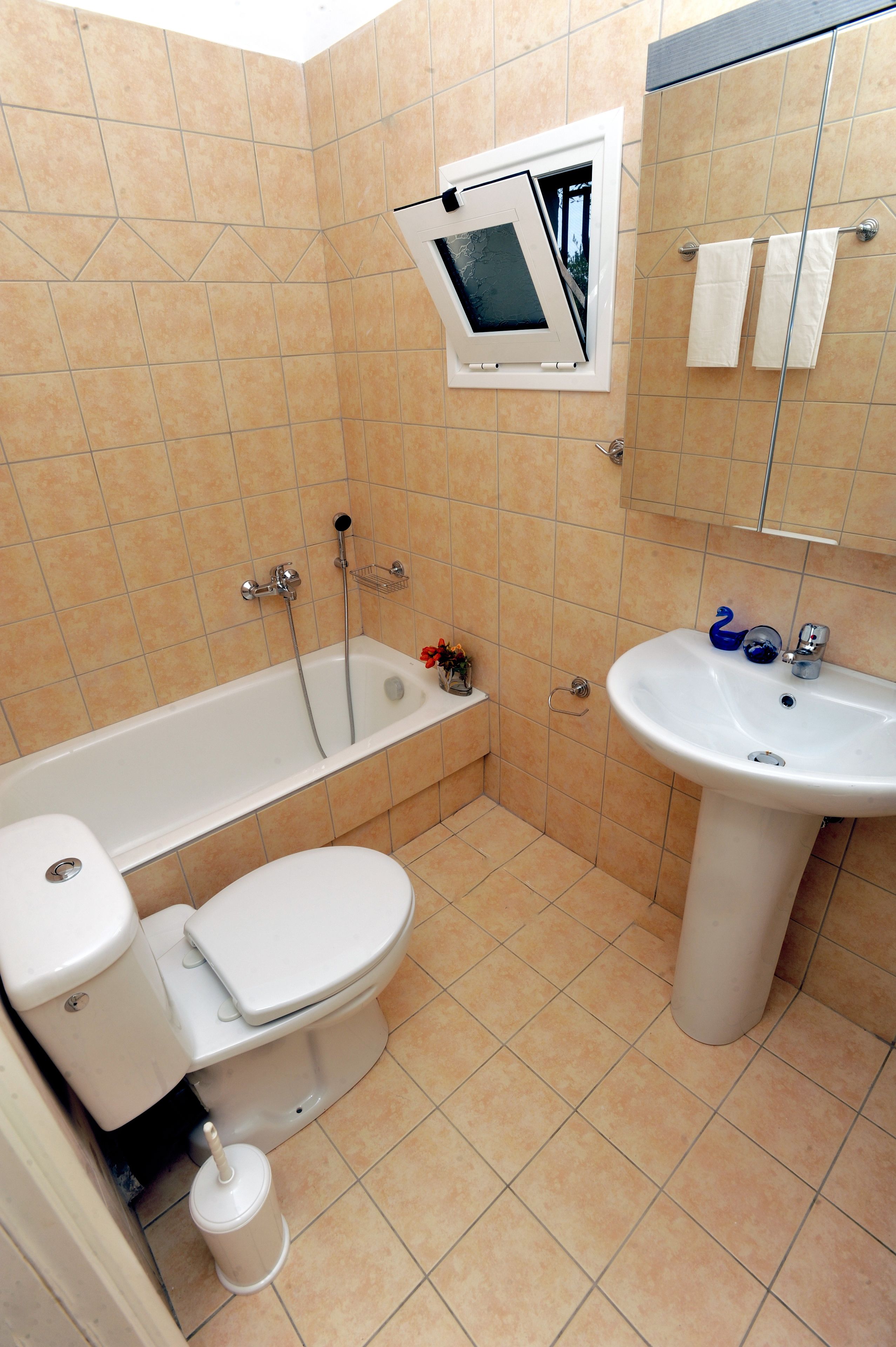 A bathroom with a bathtub, toilet, sink, and a window with a view.