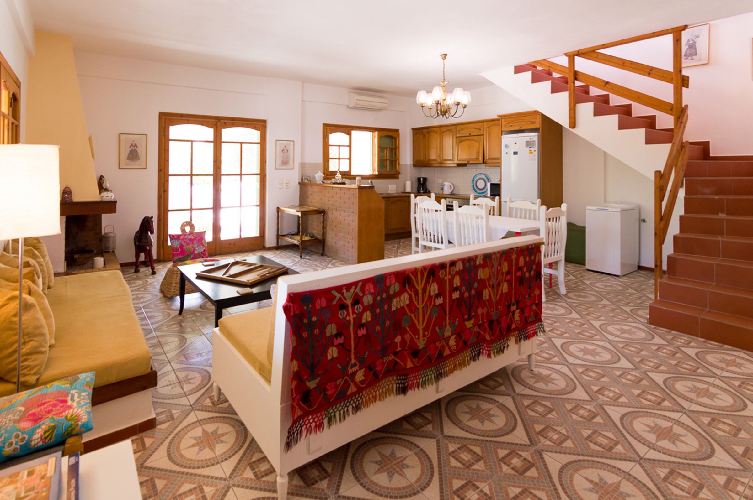 A cozy living room with a sofa, a coffee table, and a patterned rug. There is a staircase leading to an upper level.