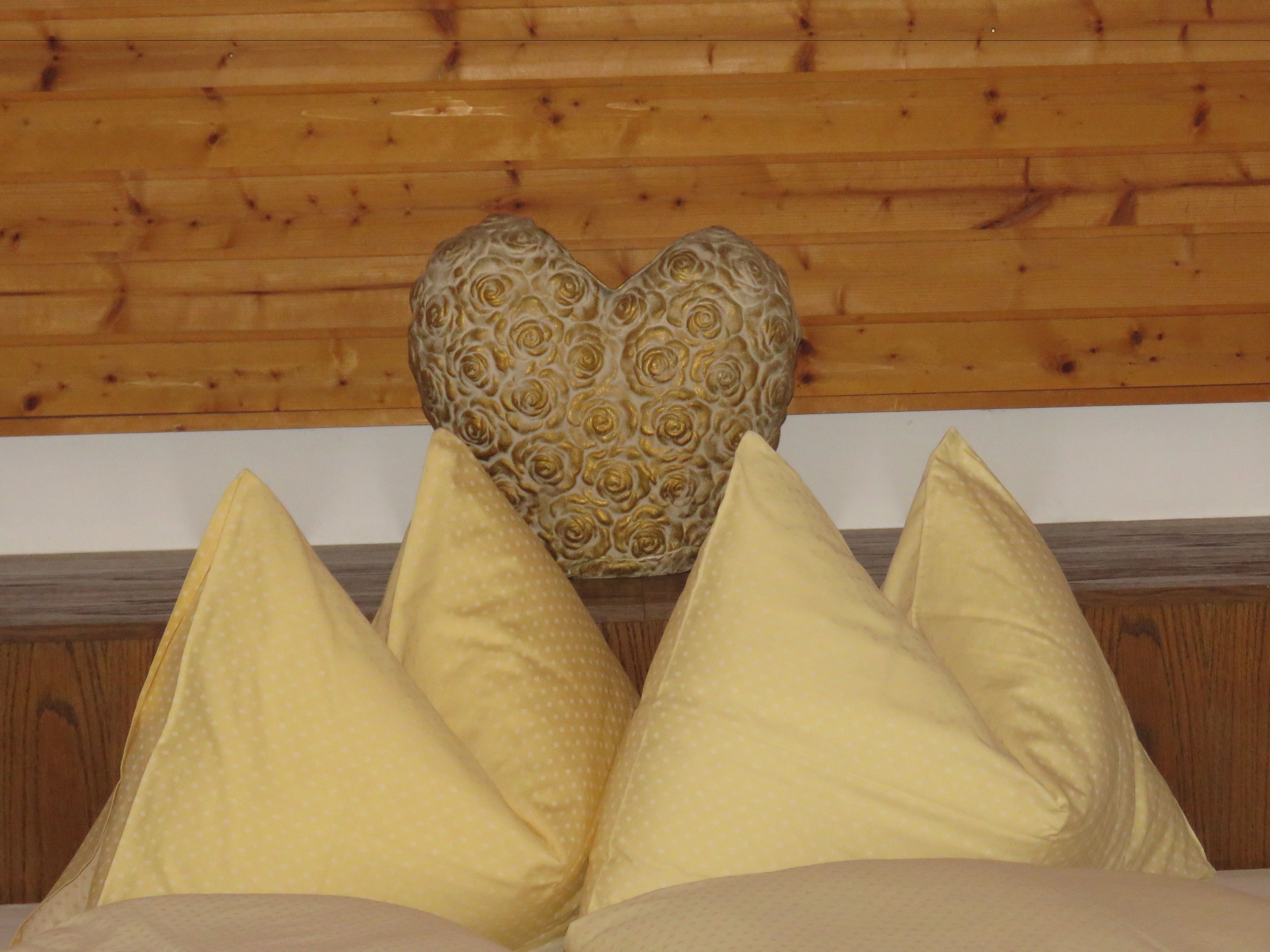 A bed with a wooden headboard and three pillows.