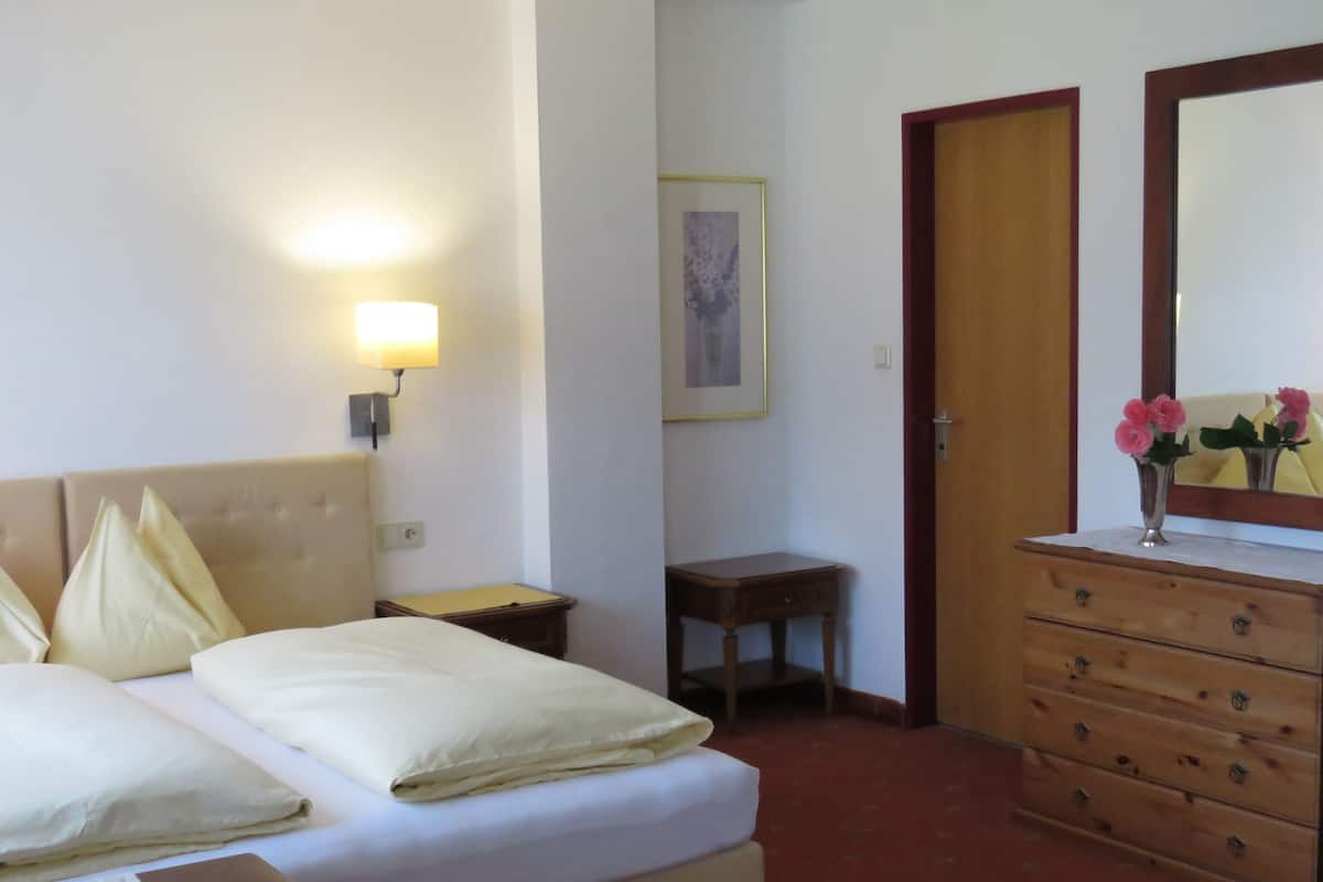 Una habitación de hotel con cama, mesita de noche, cómoda y espejo.