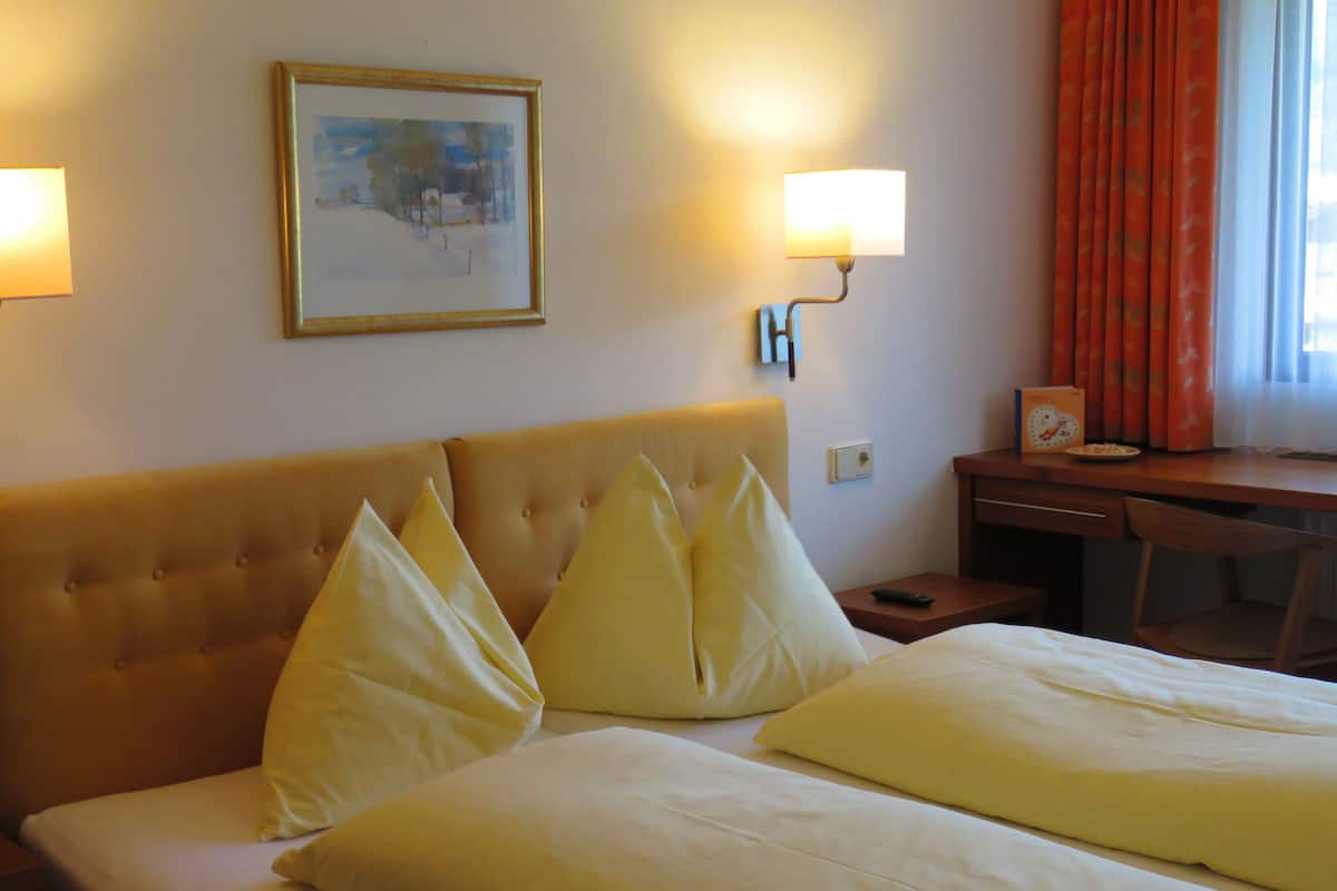 Una habitación de hotel con una cama grande, un escritorio y un cuadro en la pared.