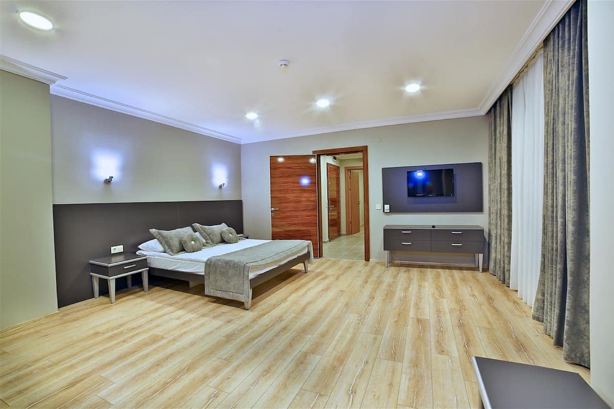 A bedroom with a bed, bedside tables, a TV, and a wardrobe.
