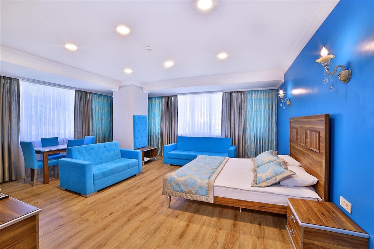 A hotel room with a bed, a blue sofa, a desk, and a chair.