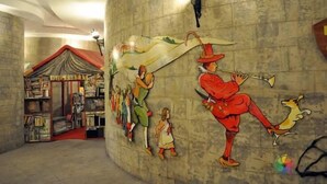 Et bibliotek med bogreoler og et muralmaleri af en mand, der spiller fløjte.