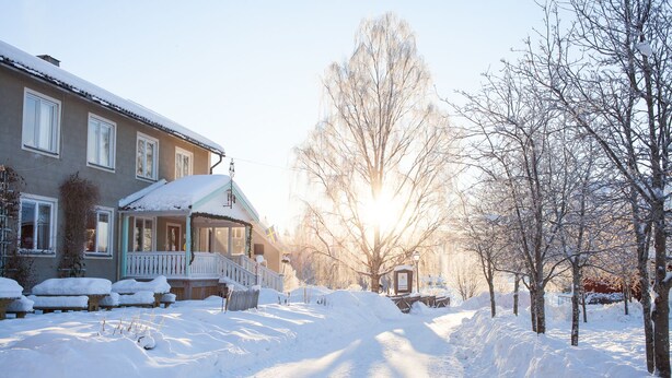 A snow-covered street with a house on the left and bare trees on the right. - Helsingegården (Jarvso)