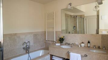 Ein modernes Badezimmer mit Badewanne, zwei Waschbecken, einem großen Spiegel und einem Handtuchhalter.