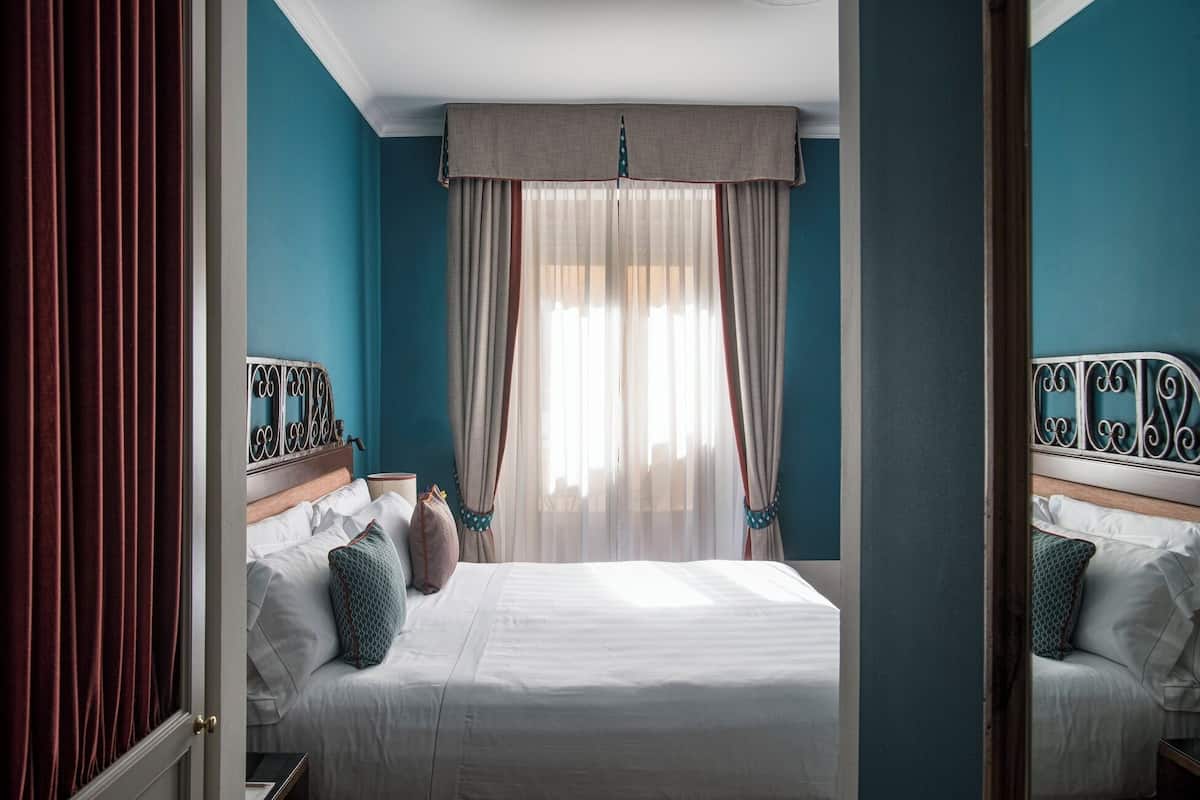 A bedroom with a bed, curtains, and a headboard.