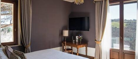Un dormitorio con una cama grande, un televisor montado en la pared, una mesita con lámpara y vistas al exterior a través de una puerta corredera.