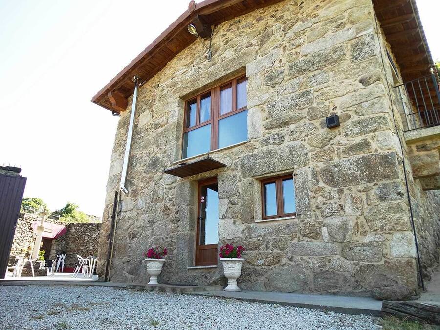 A stone building with a wooden door, two windows, and potted plants.