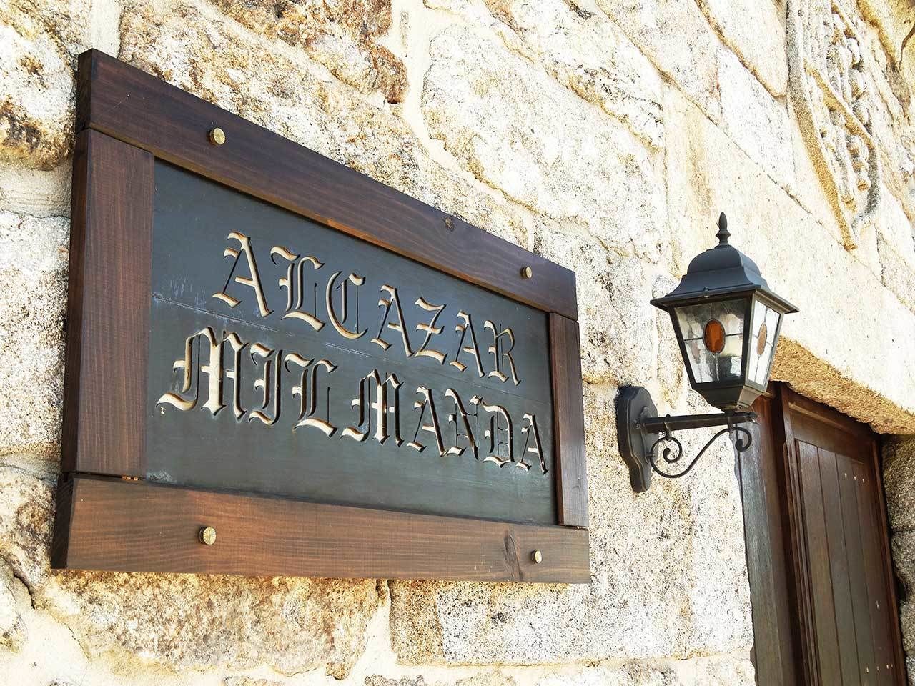 A wooden sign with carved text on a stone wall, a traditional lantern, and a wooden door.