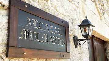 A wooden sign with carved text on a stone wall, a traditional lantern, and a wooden door.