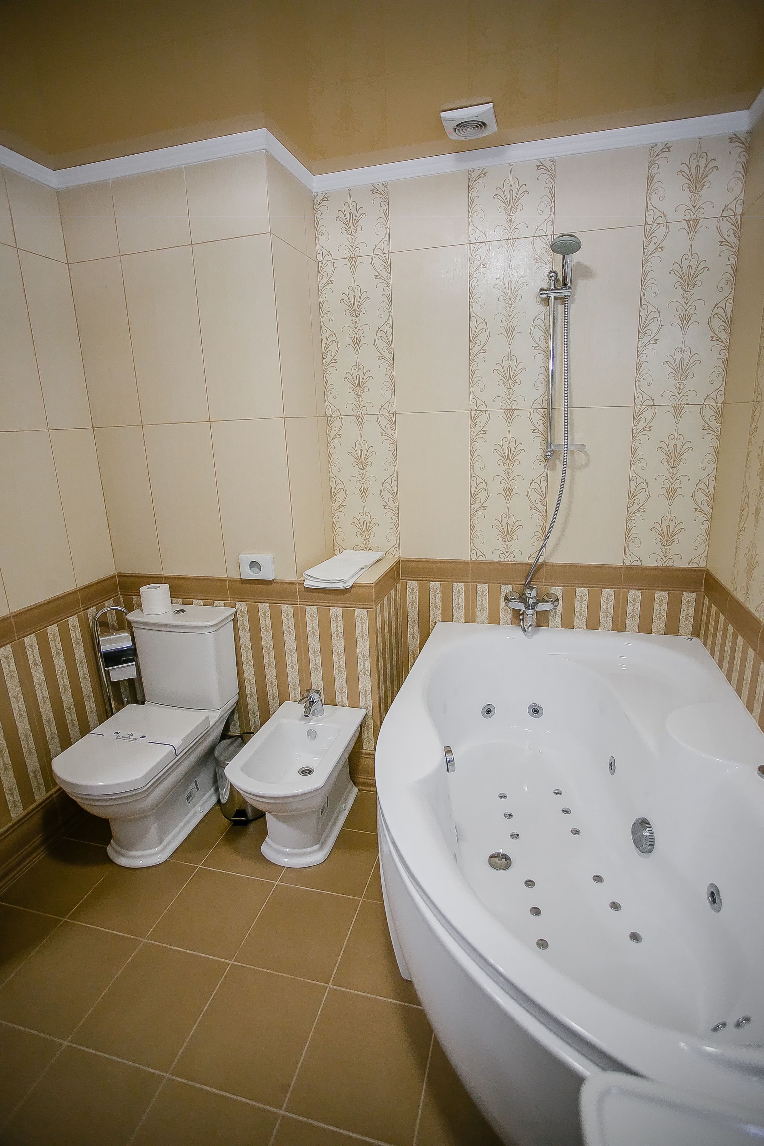 A bathroom with a bathtub, two toilets, and a shower.