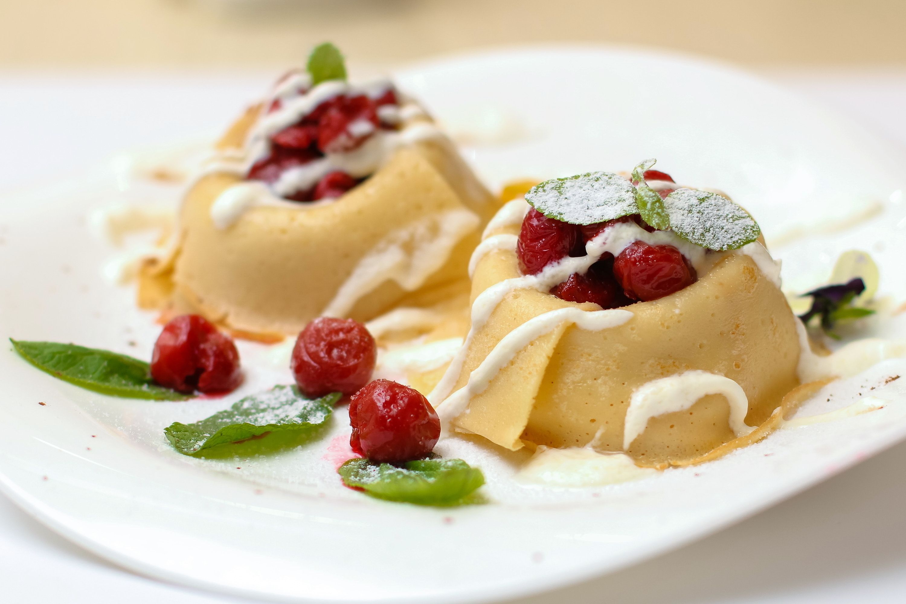 A dessert with cream and raspberries on a white plate.