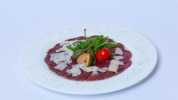 Un plato de carne cruda con verduras y queso.